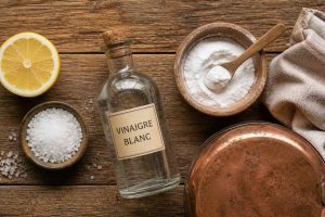 Ingrédients naturels pour nettoyer le cuivre : citron, sel, vinaigre blanc, bicarbonate de soude et chiffon doux sur une surface en bois rustique. Toutes les astuces de grand-mère pour redonner de l'éclat au cuivre et au laiton