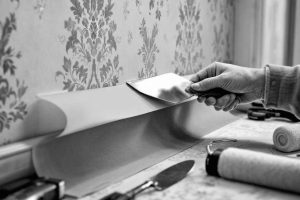 Pose papier peint vintage intissé : appliquer un lé au mur avec spatule. Tutoriel DIY pose papier peint étape par étape. Conseils bricolage décoration